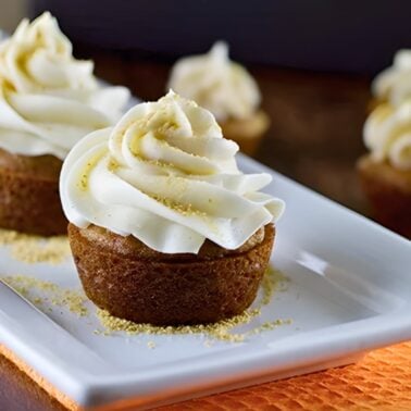 pumpkin pie cupcakes topped with cream cheese frosting and crushed graham cracker crumbs.