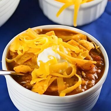 slow cooker chili served in a bowl and topped with cheese, sour cream and Fritos