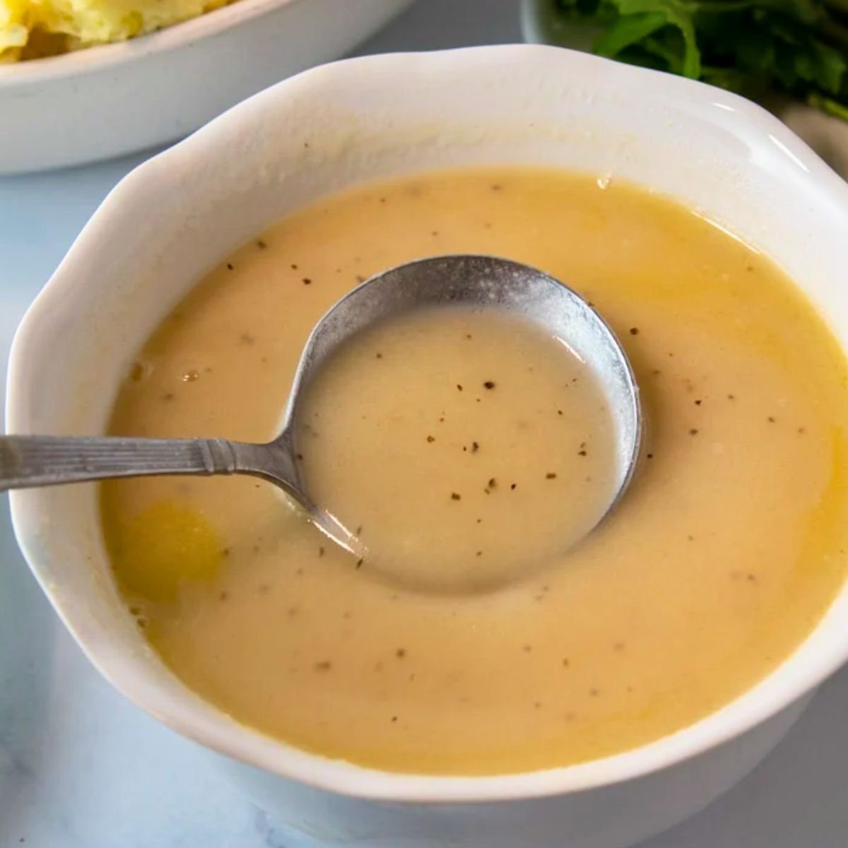 homemade turkey gravy in a small bowl with a lady,, perfect for thanksgiving dinner. 