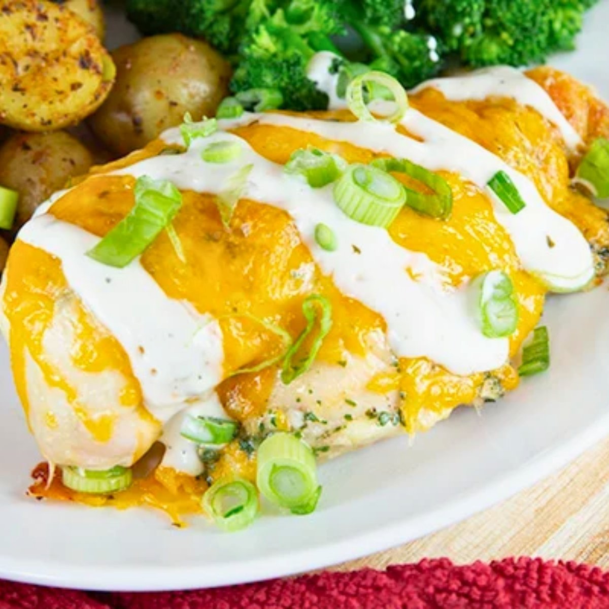 close-up of juicy baked ranch chicken breasts seasoned with a packet of ranch seasoning mix served on a plate with potatoes and broccoli.