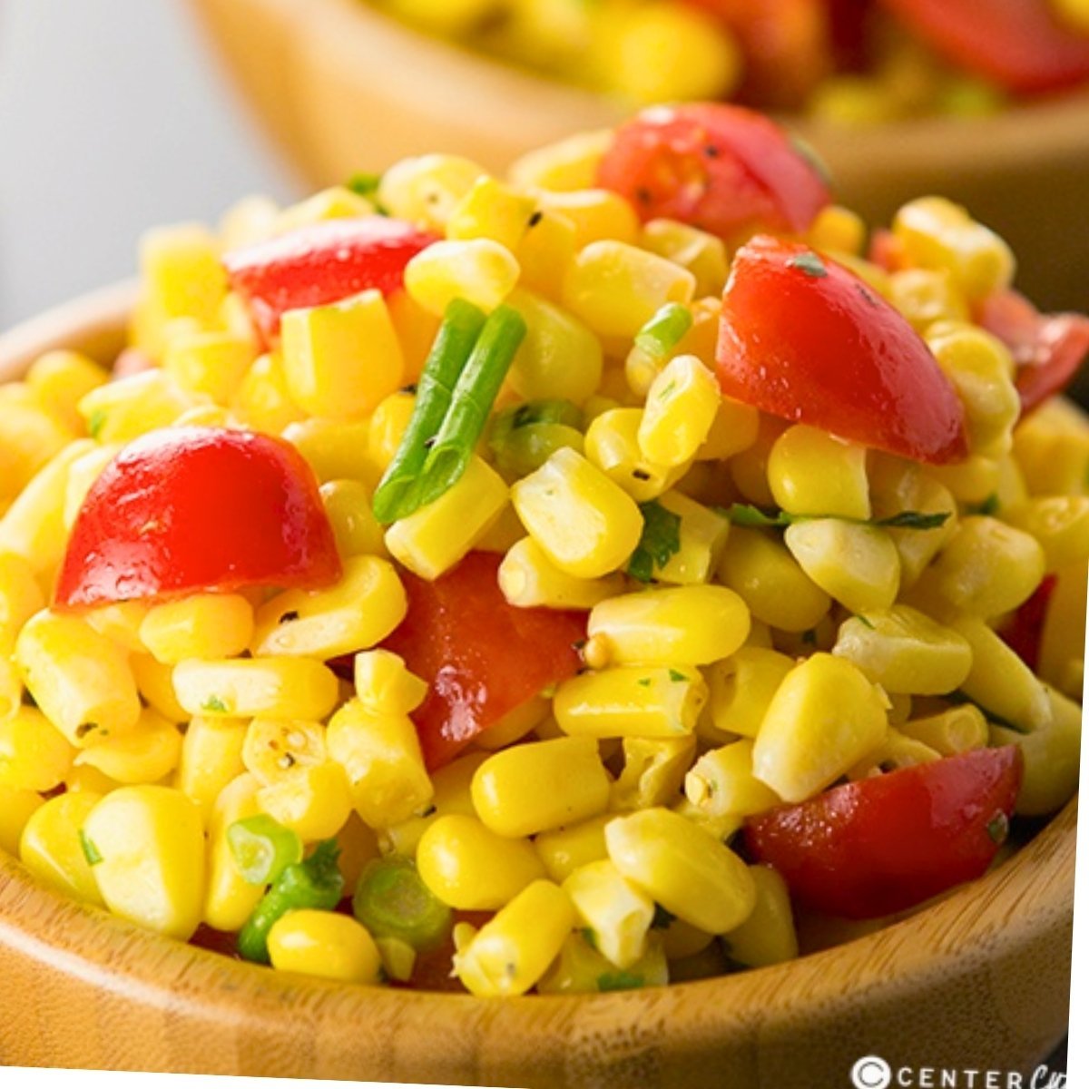 a bowl of fresh corn salad with sweet corn, tomatoes, green onion, and cilantro.