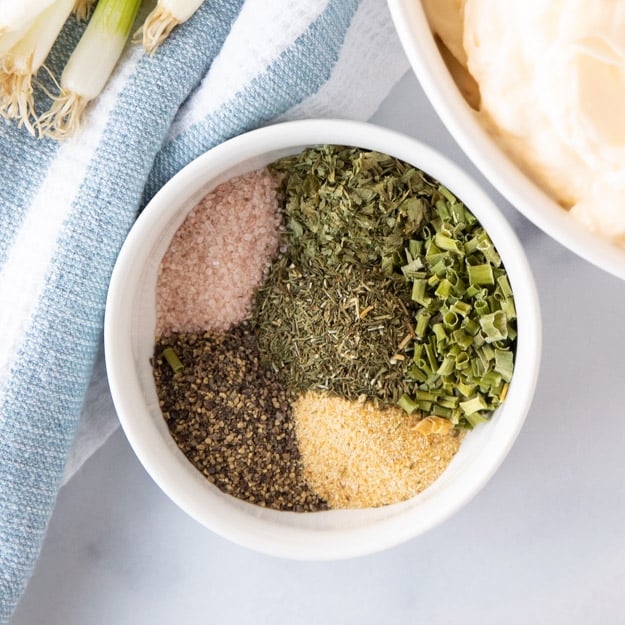 a bowl of fresh herbs and seasonings used to make ranch dip