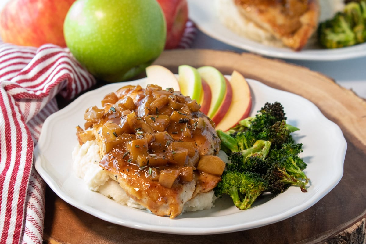 plate of chicken with apple cider sauce, apple slices, and broccoli