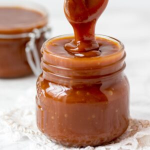 jar of homemade caramel with spoon pulling out of jar