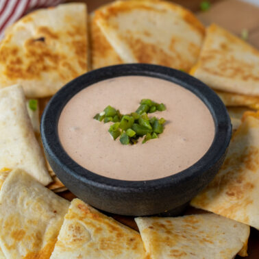 Taco Bell quesadilla sauce in a bowl surrounded by quesadillas
