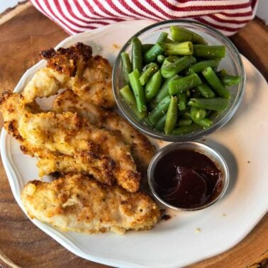 plate of air fryer parmesan crusted chicken with side of green beans and dipping sauce