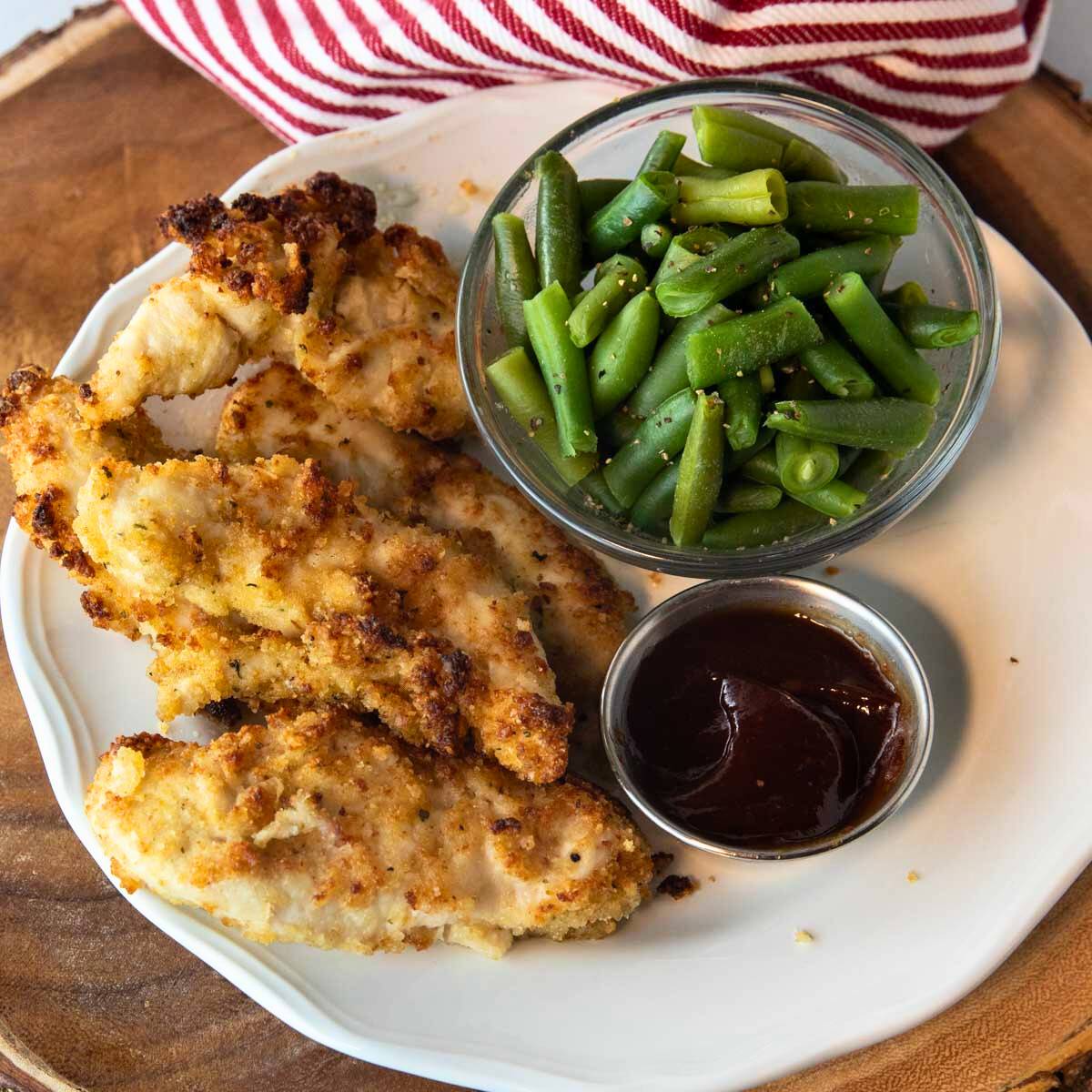 plate of air fryer parmesan crusted chicken with side of green beans and dipping sauce