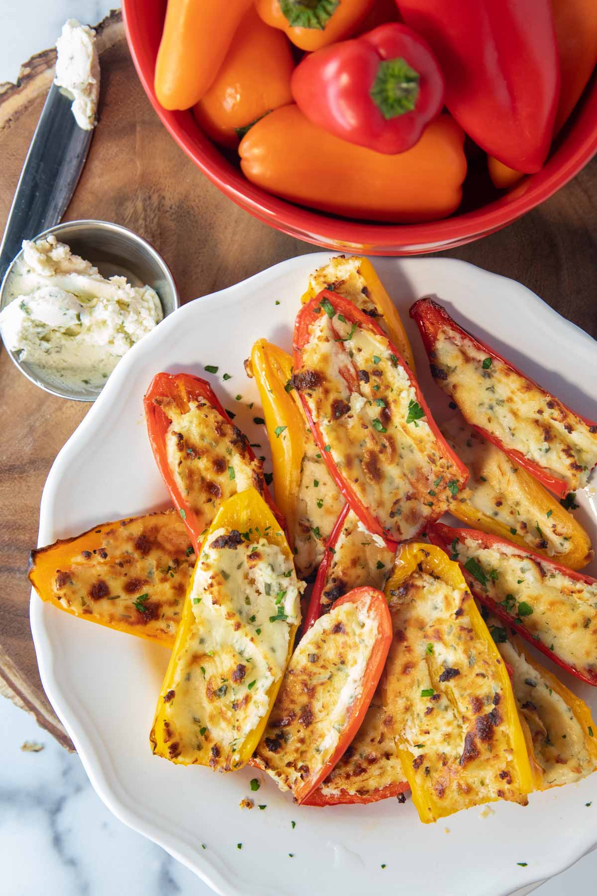 overhead of plate of air fryer stuffed mini peppers on a plate with bowl of peppers and boursin cheese sitting beside