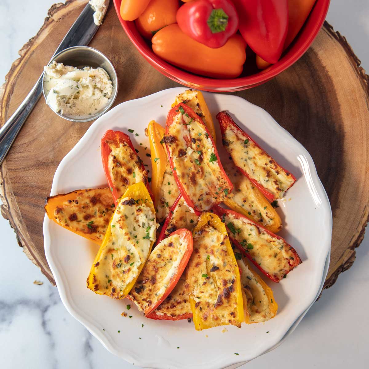 overhead of plate of air fryer stuffed mini peppers on a plate with bowl of peppers and boursin cheese sitting beside