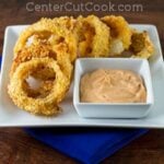 crispy baked onions rings on a plate with dipping sauce