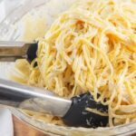 bowl of creamy alfredo sauce and pasta with tongs