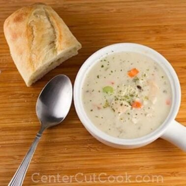 bowl of Cream of Chicken & Wild Rice Soup with a spoon and bread sitting beside