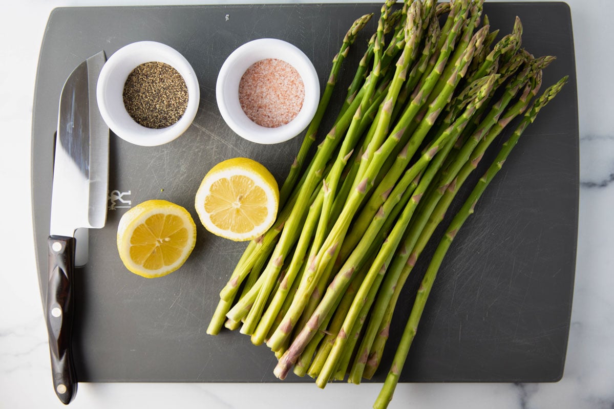 overhead of cutting board of grilled asparagus ingredients and a knife