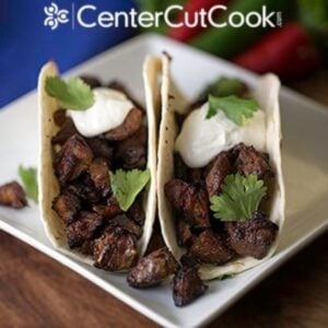 plate of the best pork carnitas topped with cilantro and sour cream