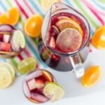 overhead of pitcher and glasses of virgin sangria and fresh lemons, limes, and oranges.