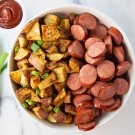 overhead of bowl of air fryer kielbasa and potatoes with a side of ketchup