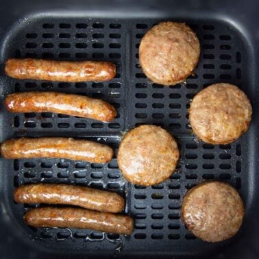 breakfast sausage patties and links cooking evenly in an air fryer basket.