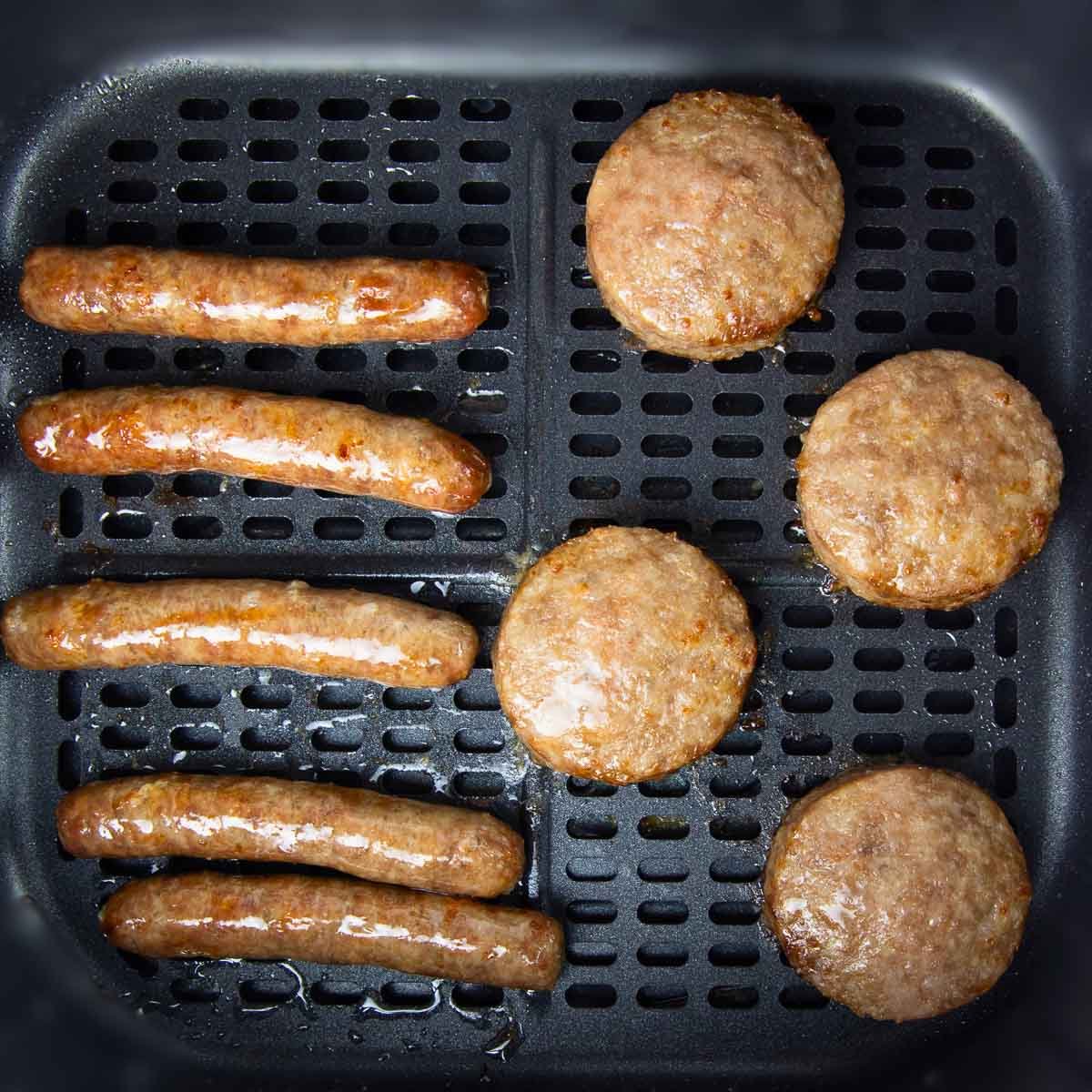 breakfast sausage patties and links cooking evenly in an air fryer basket.