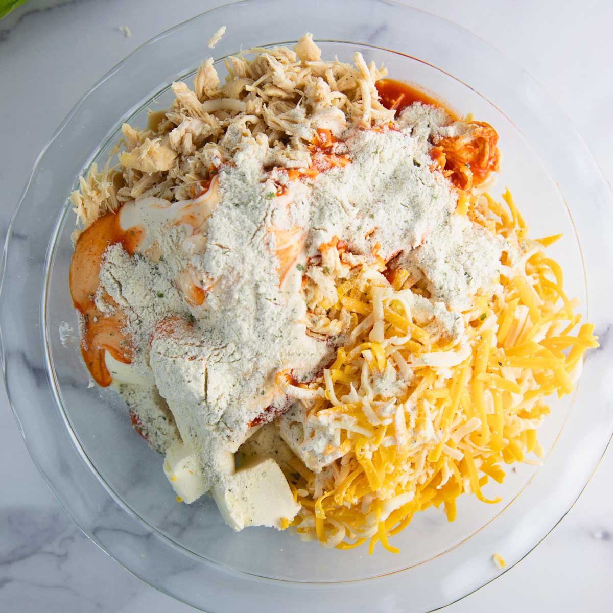ingredients for buffalo chicken dip in a baking dish ready to be baked.