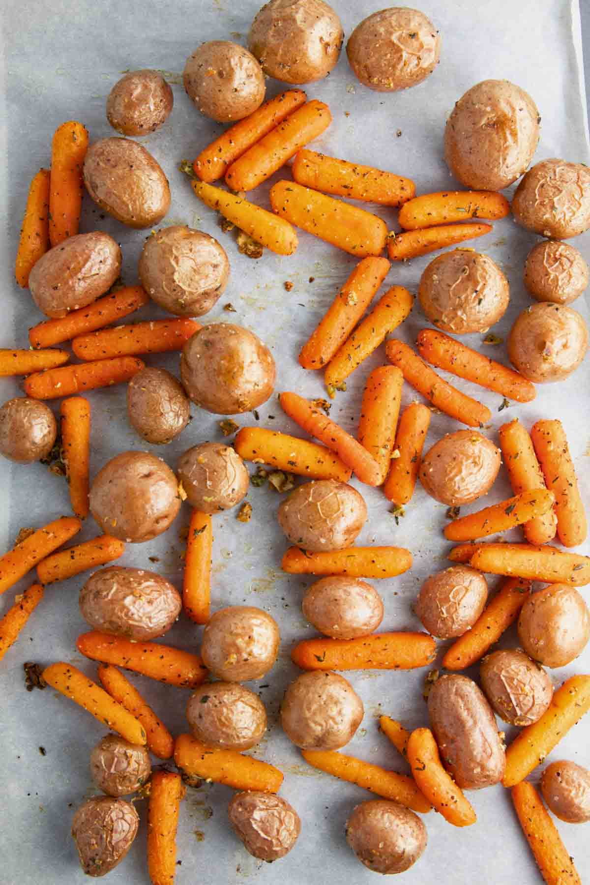 golden-brown roasted baby carrots and potatoes on a sheet pan just after they come out of the oven.