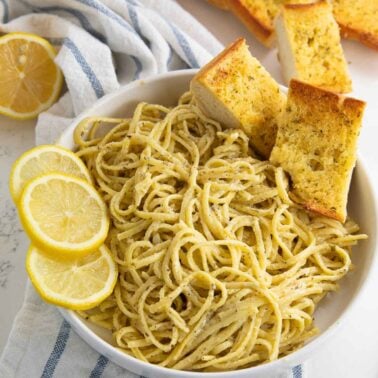 A bowl of creamy lemon butter linguini served with garlic bread.