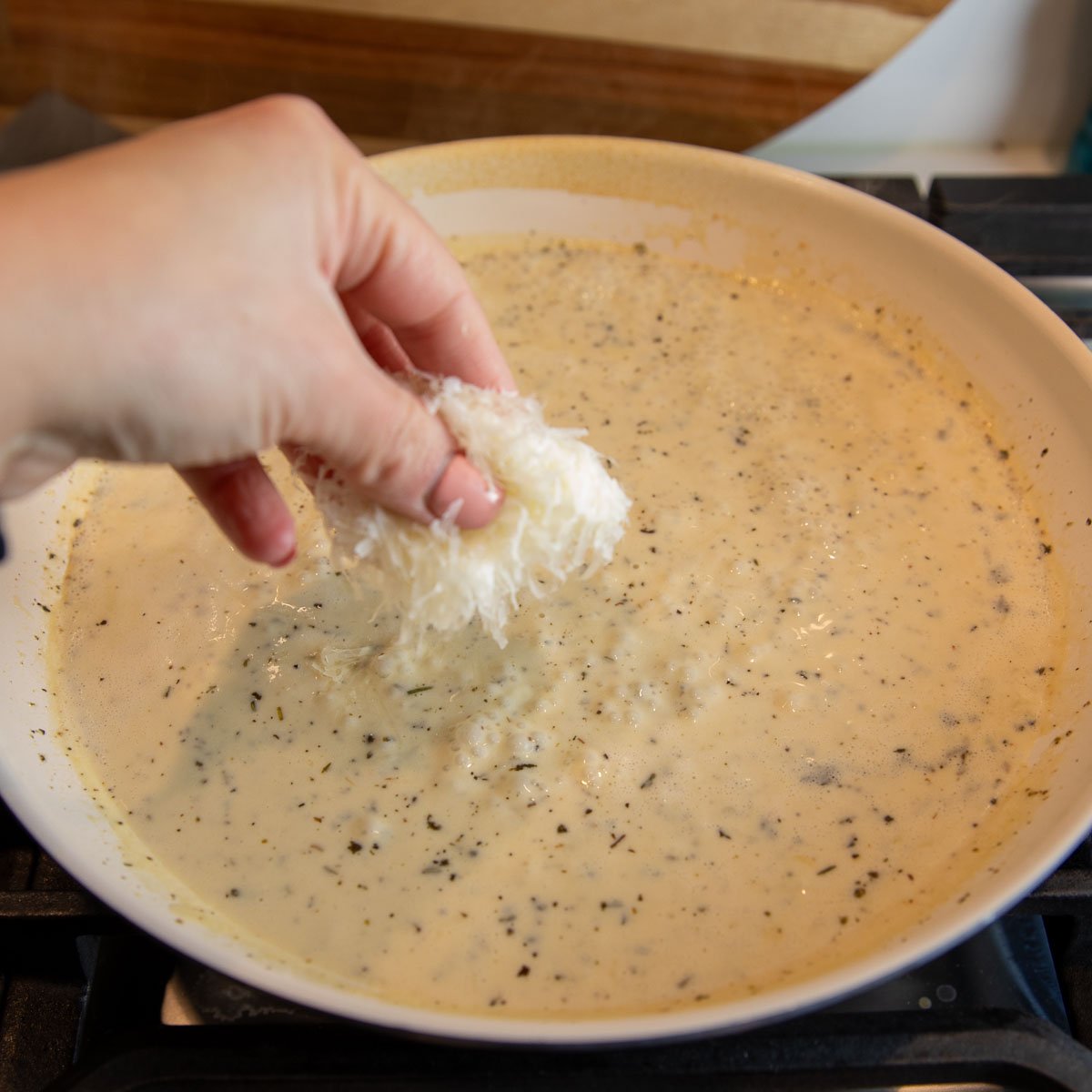 fresh parmesan cheese added to a pan to make creamy lemon butter sauce for pasta