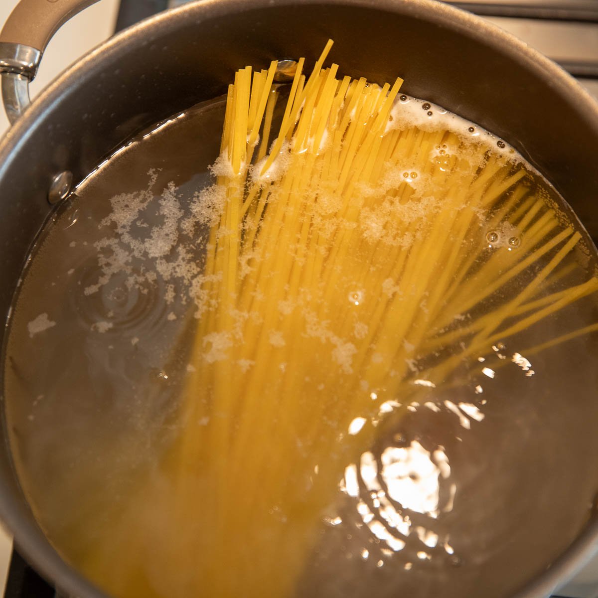 a pot of boiling water cooking linguini to al dente