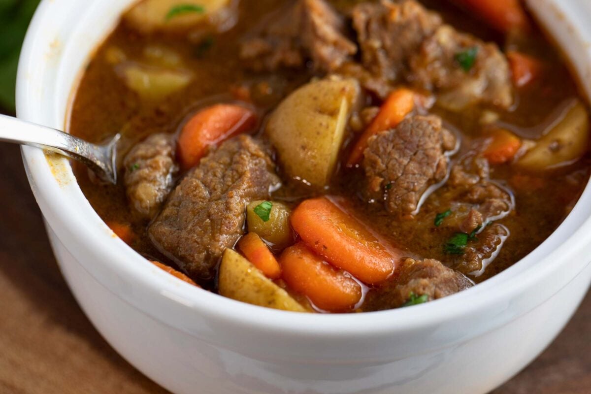 hearty beef stew in a bowl with a sprinkle of parsley on top.