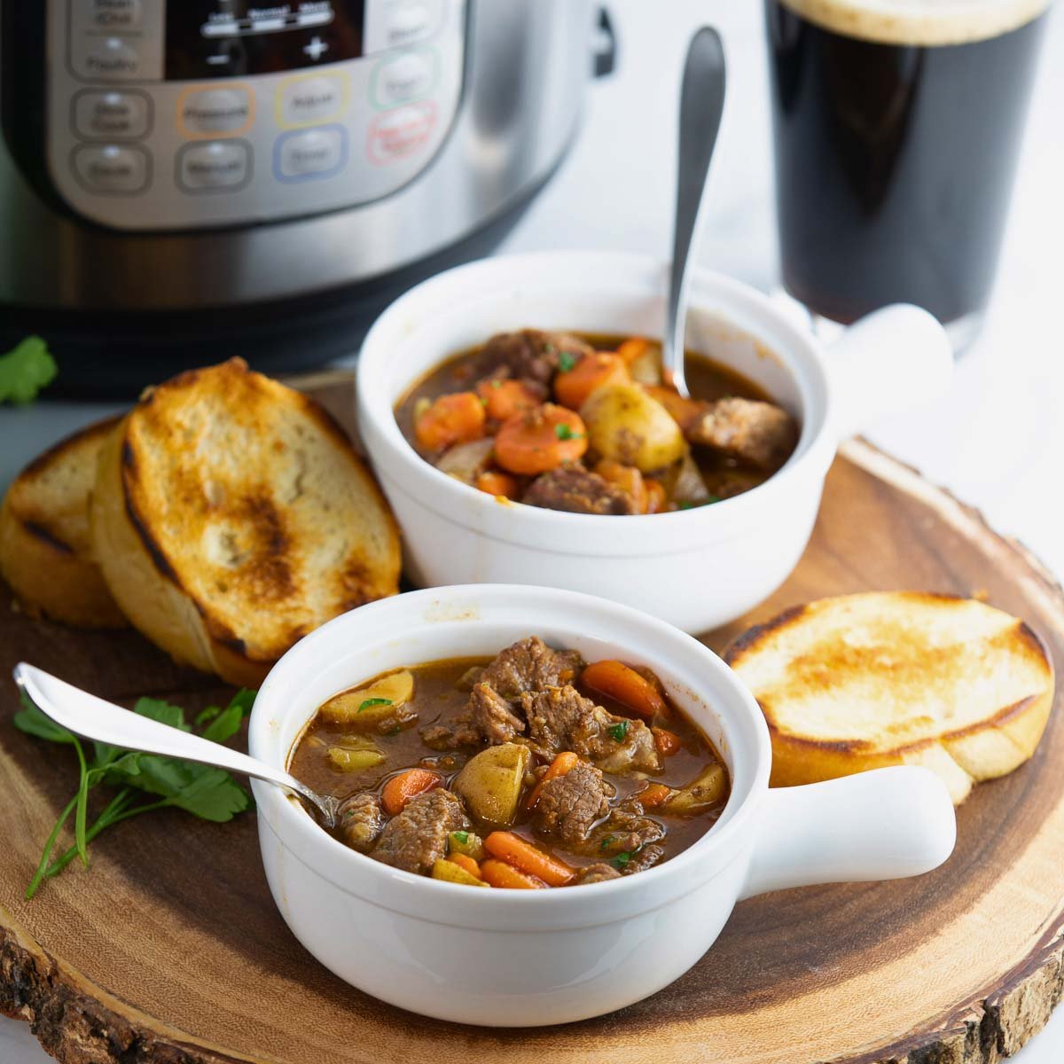 Instant Pot Irish beef stew served with crusty bread and fresh parsley for garnish.