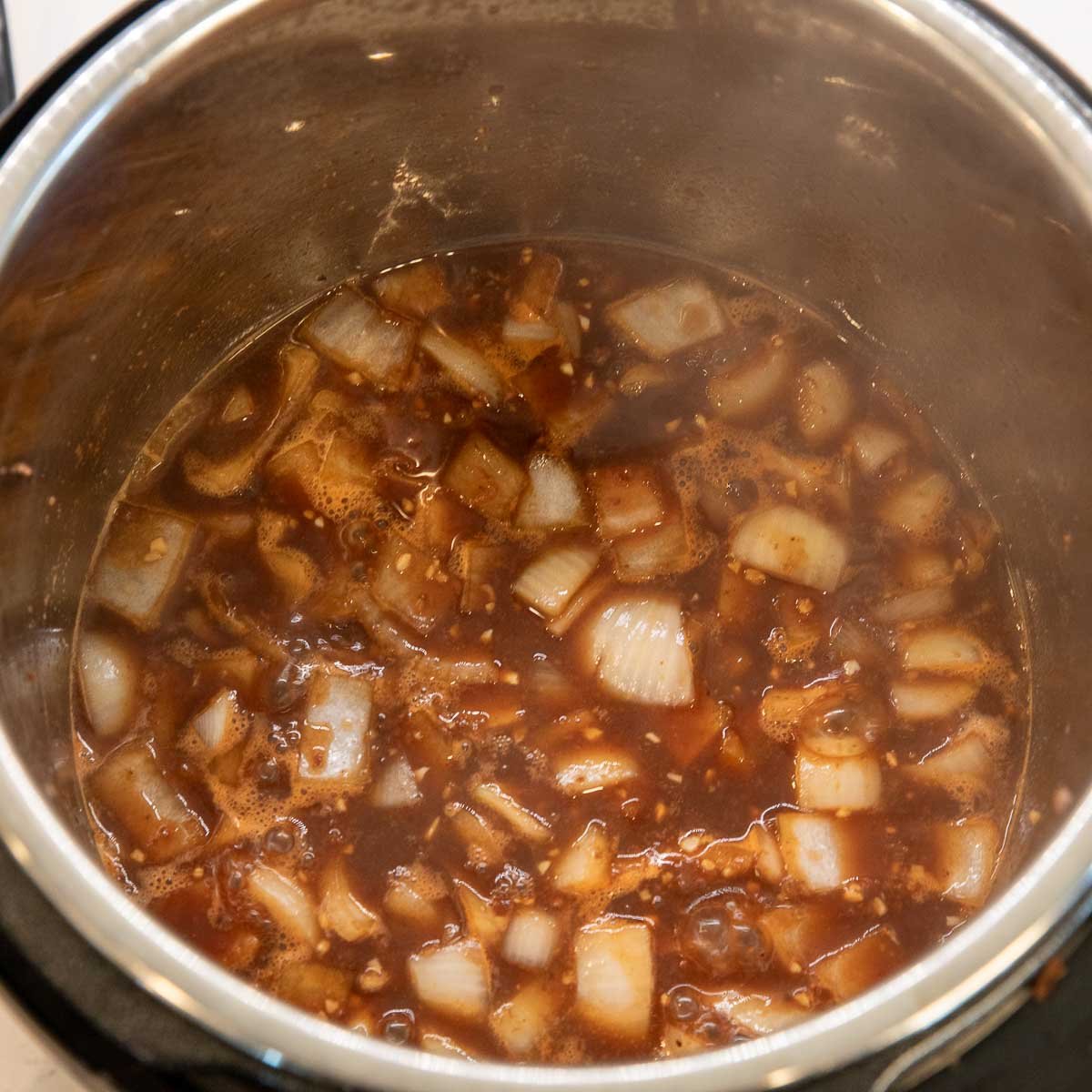 Deglazing the instant pot with Guiness beef and scraping up browned bits.