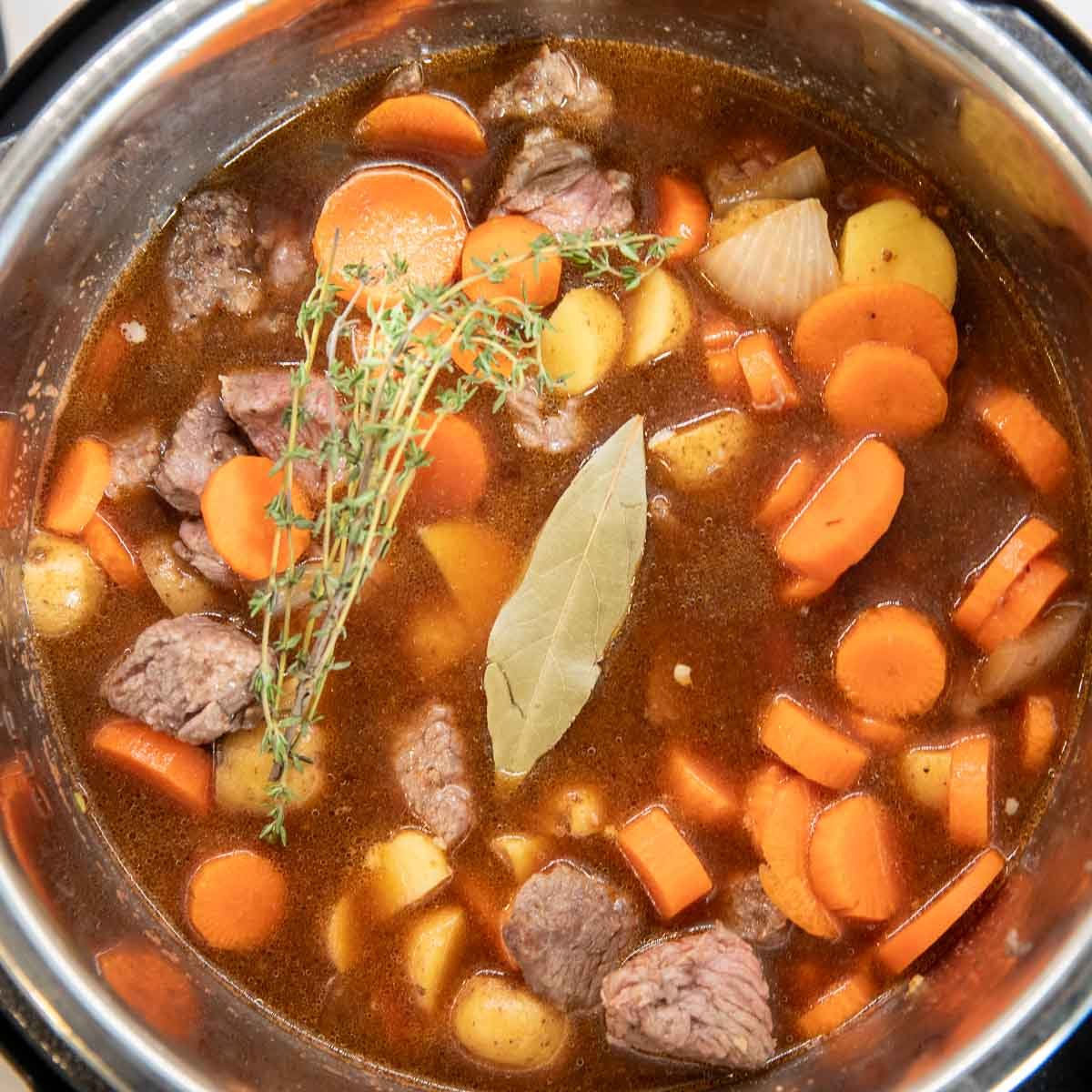 Adding fresh thyme and a bay leaf to the stew.