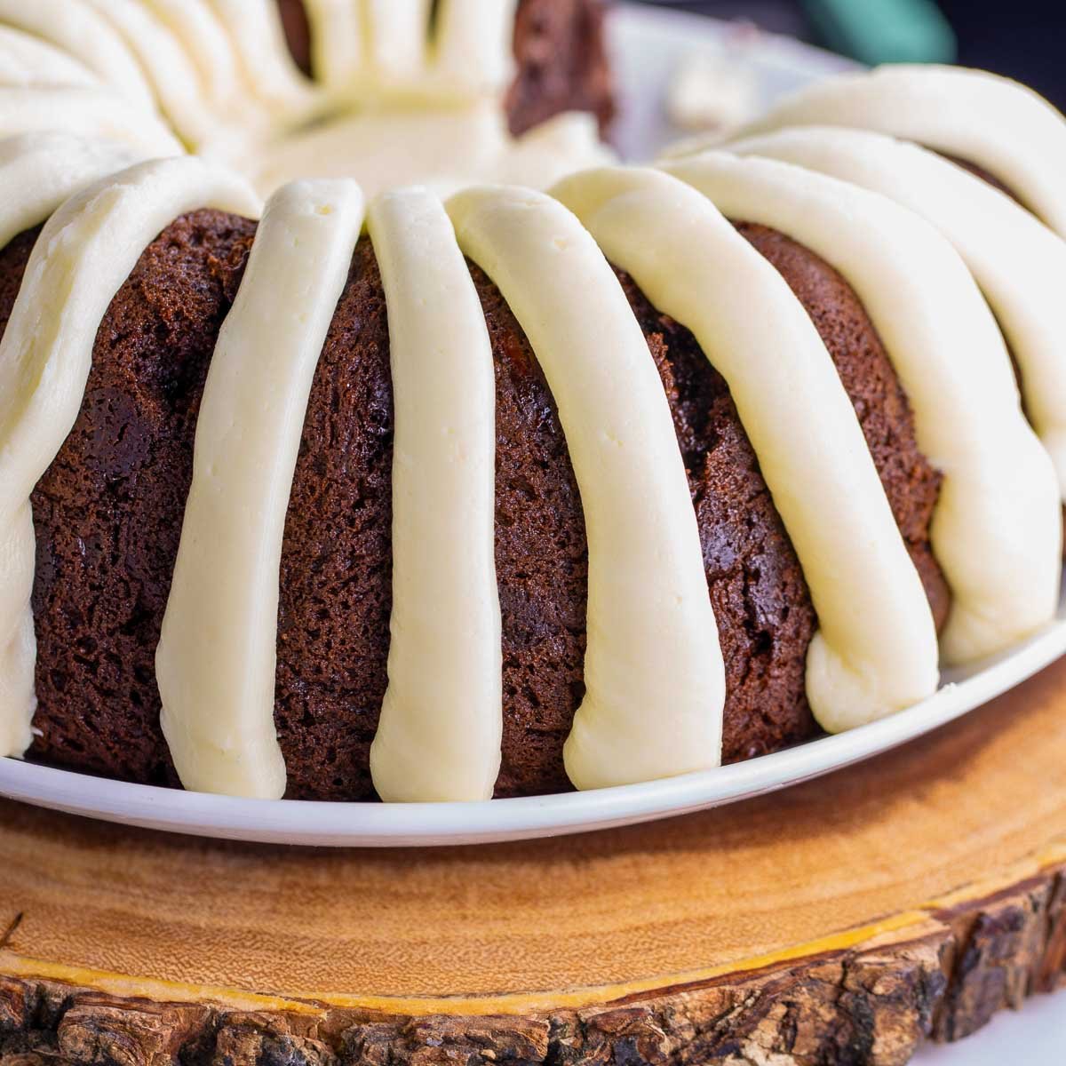 freshly baked chocolate chocolate chip Bundt Cake with cream cheese frosting on a plate ready to be served.
