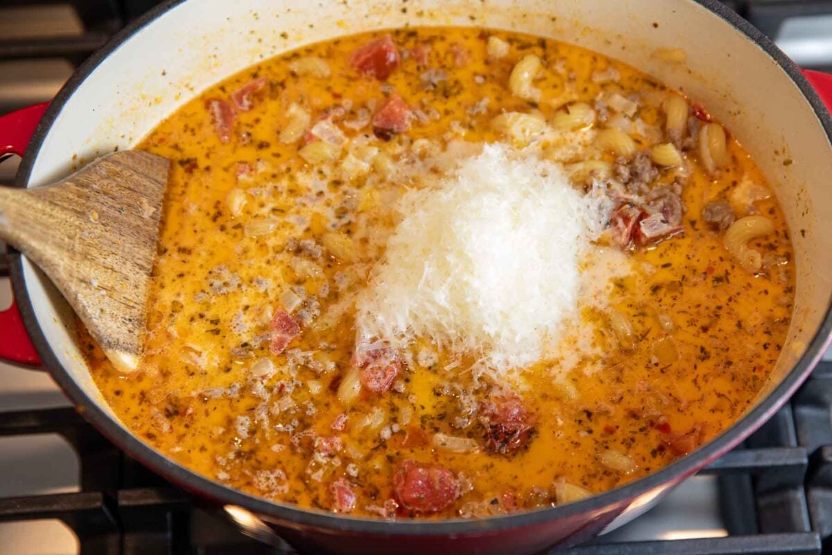 parmesan cheese and heavy cream being stirred into the soup for a rich, creamy taste