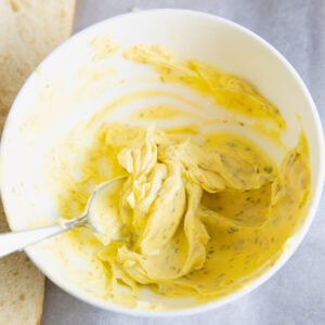 bowl of garlic bread spread made with salted butter, garlic powder and dried parsley.