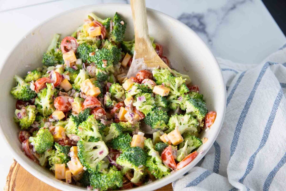 bowl of broccoli salad with bacon, cheese, tomatoes, and onions.