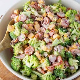 Bowl of easy broccoli salad with bacon, cheddar cheese, tomatoes and onion.