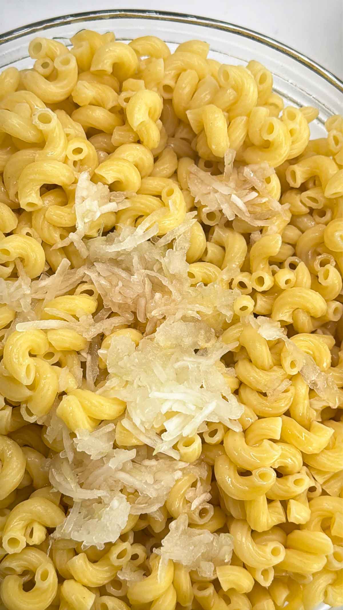 draining cooked elbow macaroni and combining it with grated onion and vinegar
