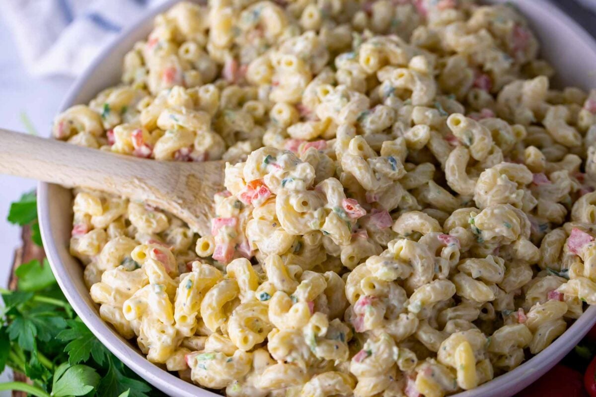 Chilled macaroni salad served in a white bowl ready for a picnic.