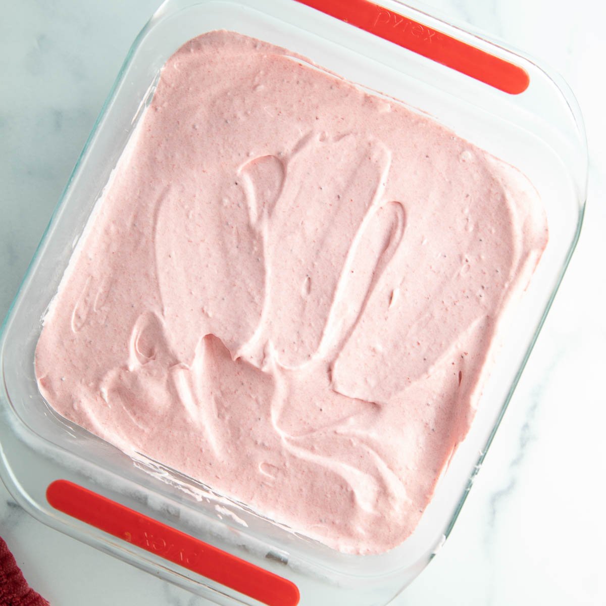 Spreading the strawberry cream cheese layer over the cookie crust.