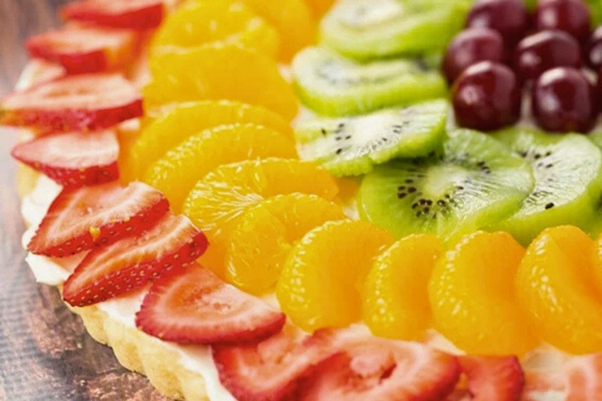 close-up of a slice of fruit pizza with cream cheese frosting.