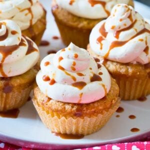 close-up of caramel apple cupcakes topped with cinnamon cream cheese frosting and drizzled with caramel sauce.