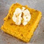 close-up of creamy pumpkin cheesecake bars with graham cracker crust and whipped cream topping