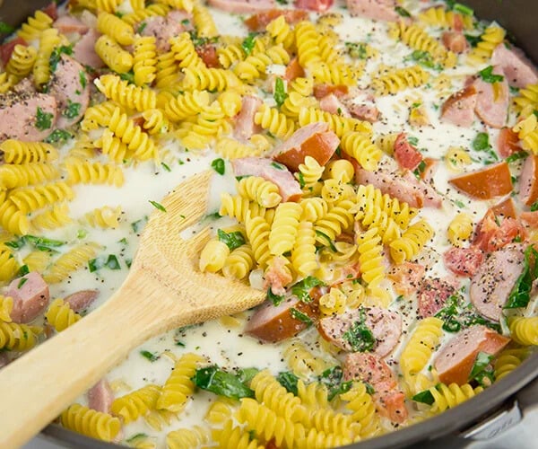 pasta simmering with sausage, tomatoes, and spinach in chicken broth and heavy cream.