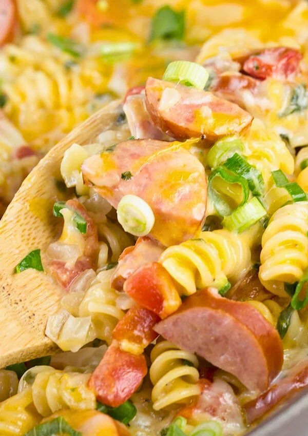 cheesy spicy sausage pasta being served from a skillet