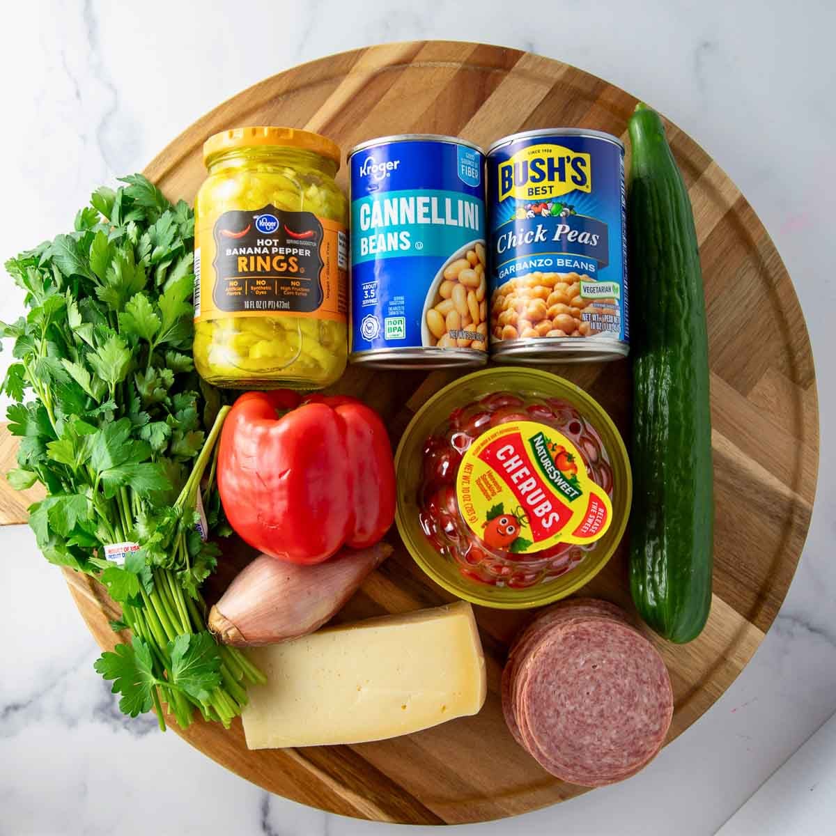 Ingredients for Italian Dense bean salad including chickpeas, cannellini beans, salami, cucumber, tomatoes, parmesan, and banana peppers