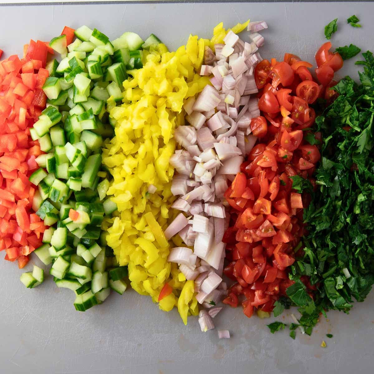 chopped cucumber, tomatoes, red bell pepper, shallot and parsley for Italian dense bean salad.